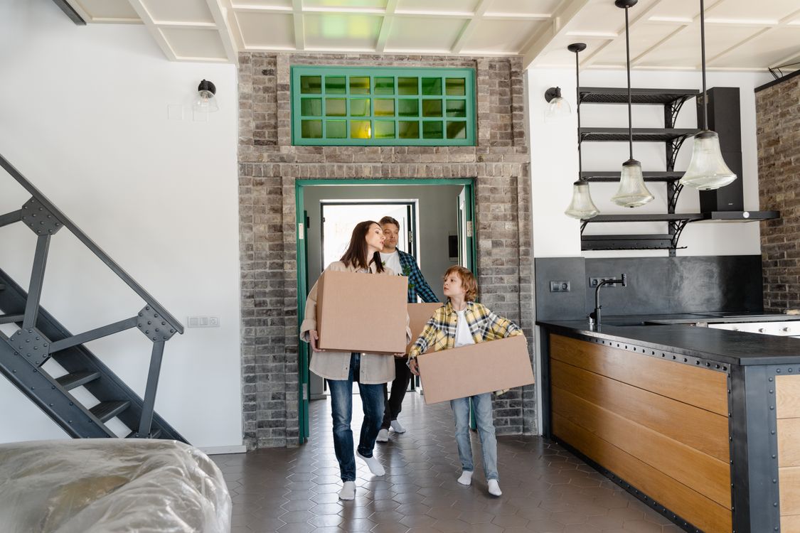 Une mère et son enfant portant des cartons de déménagement dans la cuisine de leur nouvelle maison
