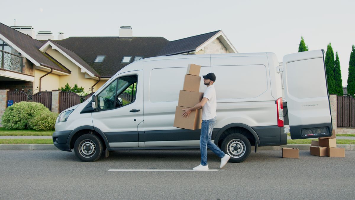Homme transportant des cartons à côté d'un camion de déménagement blanc